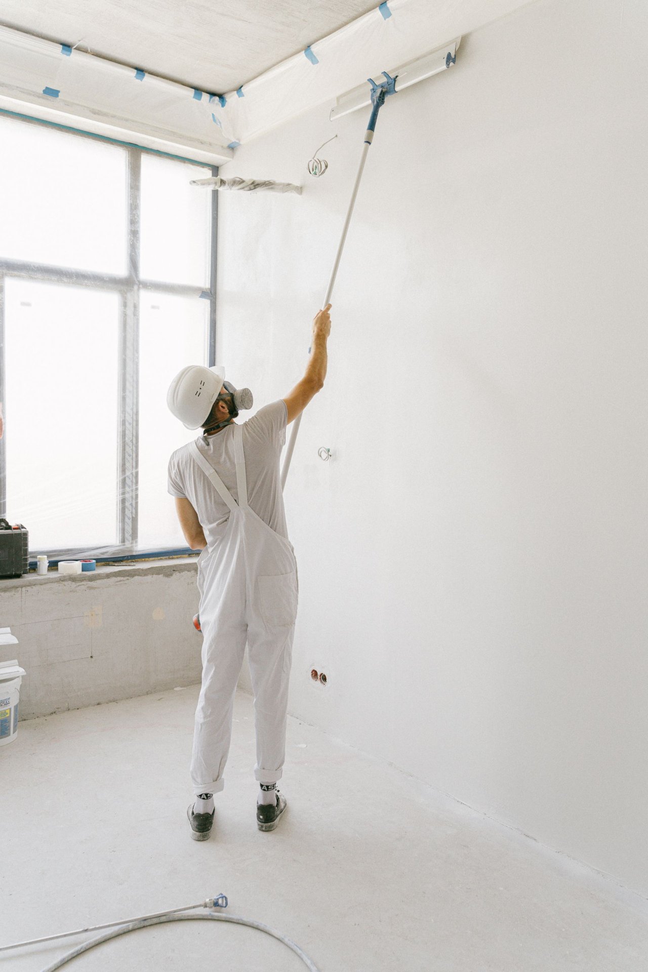 Painter using an extension roller in a room under renovation — illustrative image