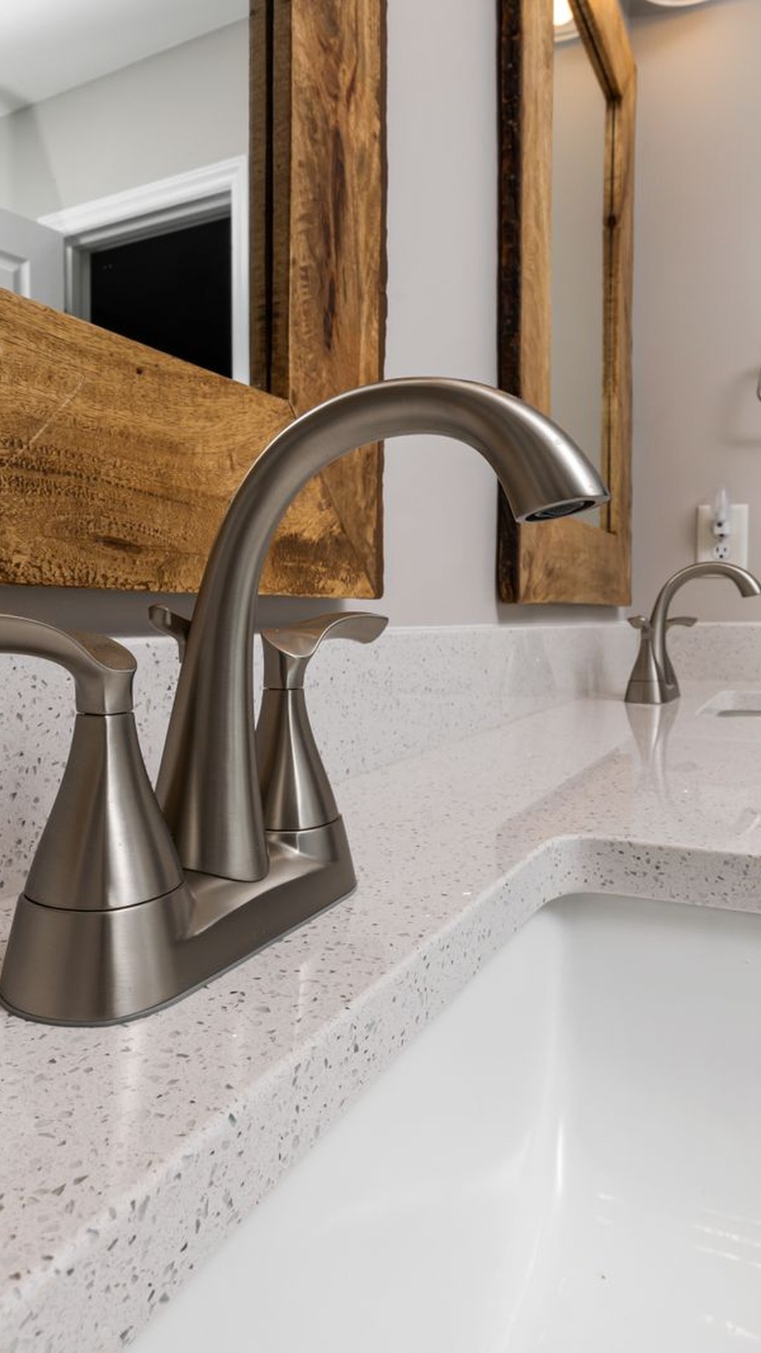 Residential bathroom faucet and sink with a natural wood mirror frame — illustrative image
