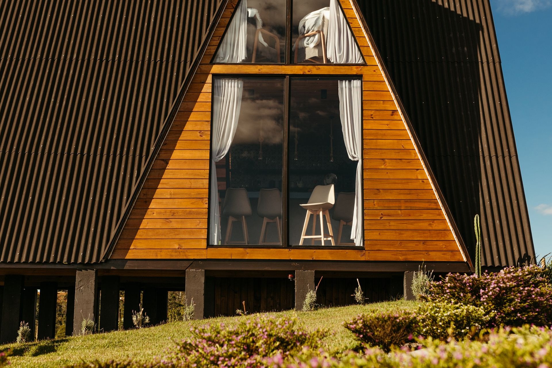 Timber residence with large triangular windows and glazed sliding doors — illustrative image